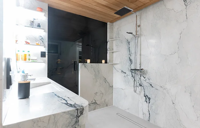 Avoin suihkutila on varustettu tyylikkäällä sadesuihkulla ja modernilla linjakaivolla, mikä takaa linjakkaan ja esteettömän lopputuloksen.